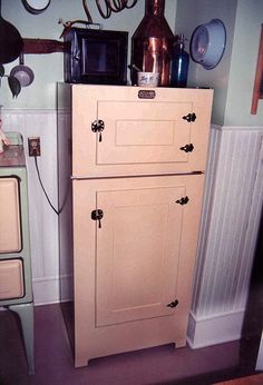 an old fashioned refrigerator in a kitchen with pots and pans hanging on the wall