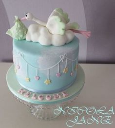 a blue cake decorated with a stork and baby's name on it