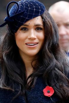 a woman wearing a blue hat with a red flower on it's side and a man in the background