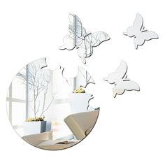 a mirror with three butterflies flying over it in front of a white wall and window