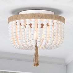 a chandelier hanging from the ceiling with beads and tassels on it