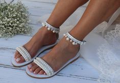 a bride's feet wearing white sandals and pearls