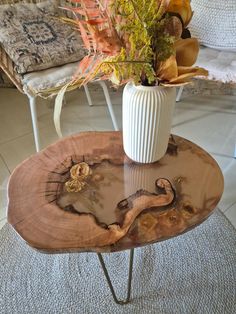 a white vase sitting on top of a wooden table next to a chair and rug