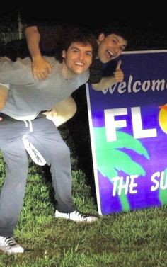 two men standing next to a welcome sign