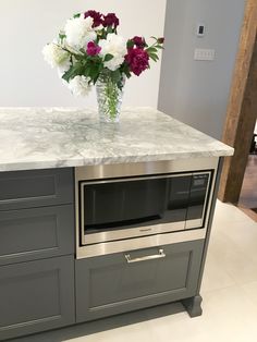 a vase with flowers sitting on top of a kitchen counter next to a microwave oven