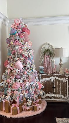 a decorated christmas tree in a living room with pink and white ornaments on it's top