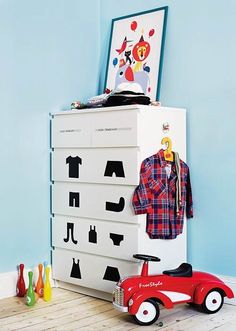 a child's toy car sits in front of a dresser with clothes on it