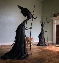 two black statues in the middle of a living room with a cat standing next to them