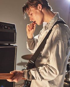 a young man holding a guitar in his right hand while standing next to an amp