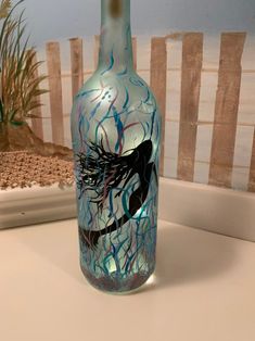 a blue glass bottle with an image of a bird on it sitting on a counter