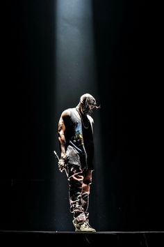 a man standing on top of a stage with his hands in his pockets and holding a skateboard