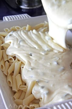 a spoon is pouring sauce over some pasta