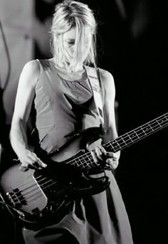 a woman playing a bass guitar on stage