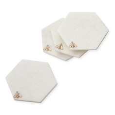 three white hexagonal coasters with gold bees on them