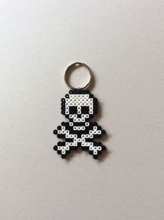 a black and white pixelated keychain with a skull on it