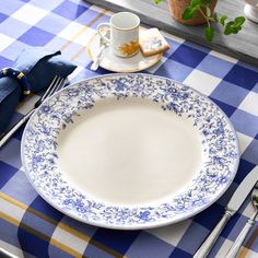 a blue and white place setting on a checkered table cloth, with silverware