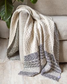 a couch with a blanket on it next to a potted plant