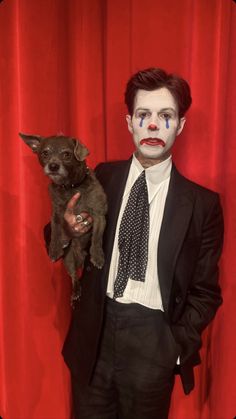 a man dressed as the joker holding a small dog