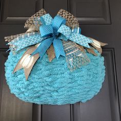 a blue and gold wreath hanging on the front door with burlocked bows