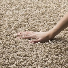 a person's hand reaching for something on the floor that is covered in carpet