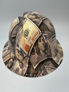 a pile of money sitting on top of a hard hat shaped like a ball cap