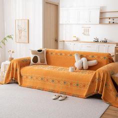 a living room with a couch covered in a yellow blanket and two stuffed animals sitting on top of it