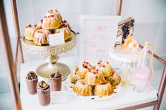 a table topped with lots of pastries on top of a metal tray next to a sign