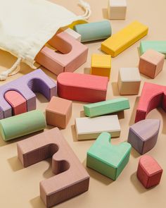 colorful wooden letters and numbers laid out on the floor next to a drawstring bag