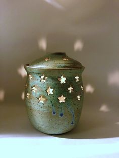 a green jar with stars on it sitting on a table next to a white wall