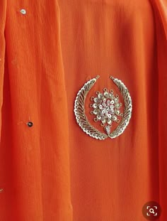 an orange dress with a silver brooch on it