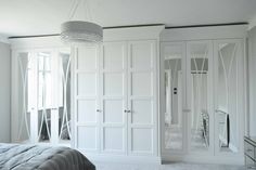 a white bedroom with mirrored closet doors and chandelier hanging from the ceiling, along with carpeted flooring