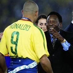 a man in a suit and tie talking to two other men on the sidelines