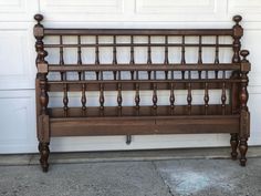 an old wooden bed frame sitting in front of a garage door on the side of a building