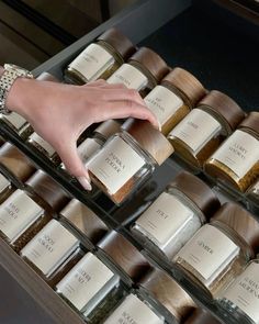 a woman's hand reaching for spices in glass containers