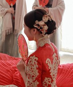 a woman in a red dress holding a mirror