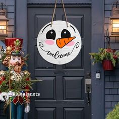 a welcome sign hanging from the side of a blue door next to a christmas tree