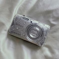 a silver camera sitting on top of a white sheet