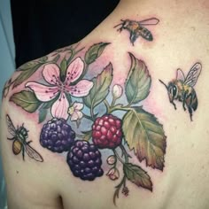 the back of a woman's shoulder with flowers, berries and bees on it