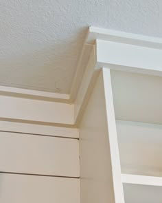 the corner of a white book shelf with an open door