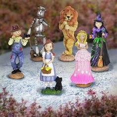 a group of miniature figurines sitting on top of a snow covered ground next to flowers