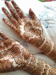 two hands with henna designs on them, one is showing off the intricate pattern