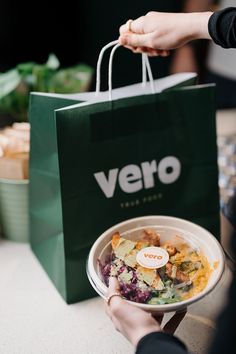 a person holding a paper bag with food in it and the words vero on it