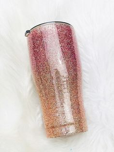 a pink and gold glitter tumbler sitting on top of a white fur covered floor