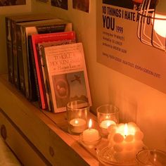 candles are lit on a shelf with books