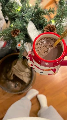 a cup of hot chocolate sitting next to a christmas tree