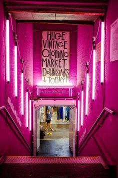 the entrance to a clothing store with pink walls and neon lights on it's sides