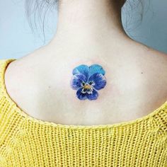 a blue flower on the back of a woman's neck is shown in this image