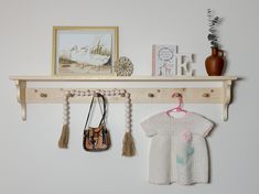 a baby's sweater hanging on a shelf with two purses next to it