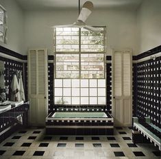 a large bathroom with black and white tiles on the floor, windows, and bathtub