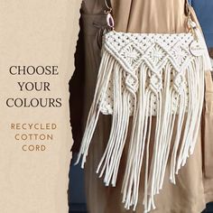 a white crocheted purse with tassels hanging from it